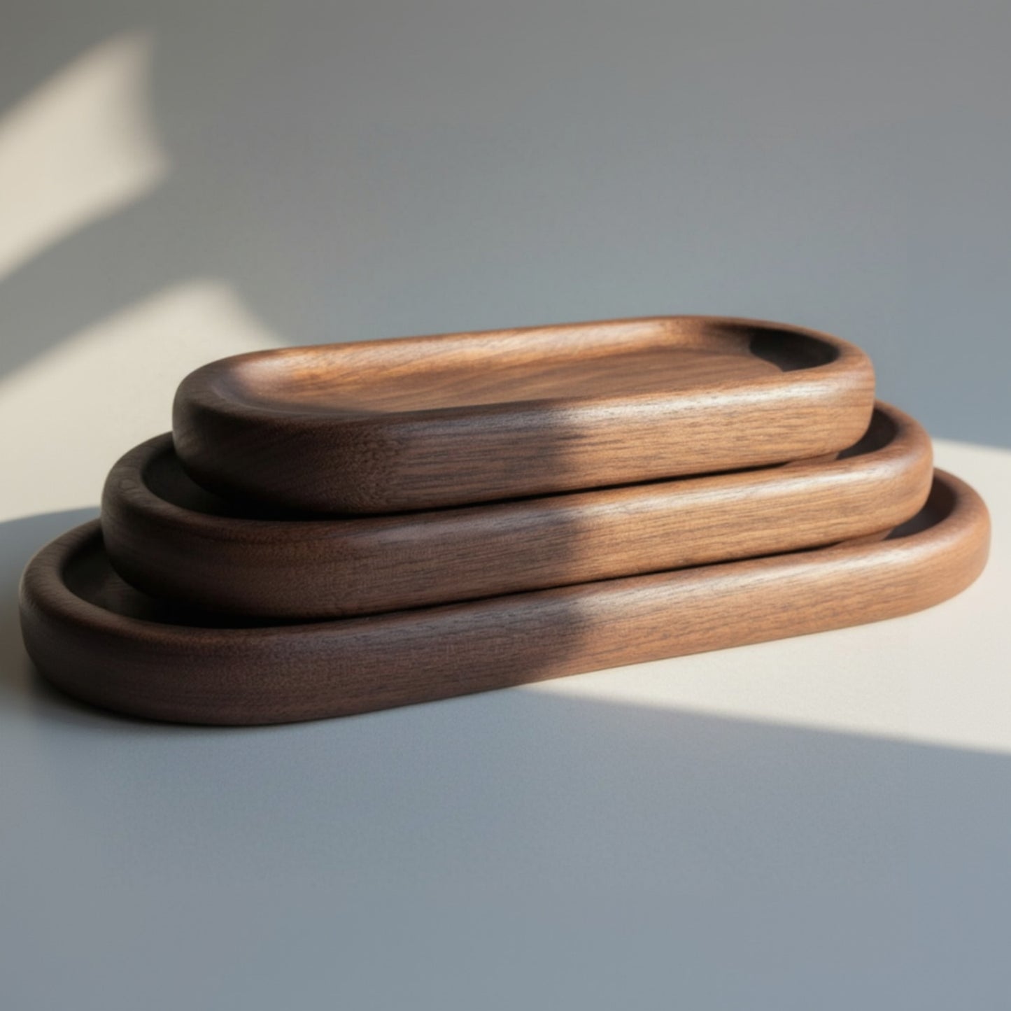 Three wooden trays of different sizes on a light wood surface.