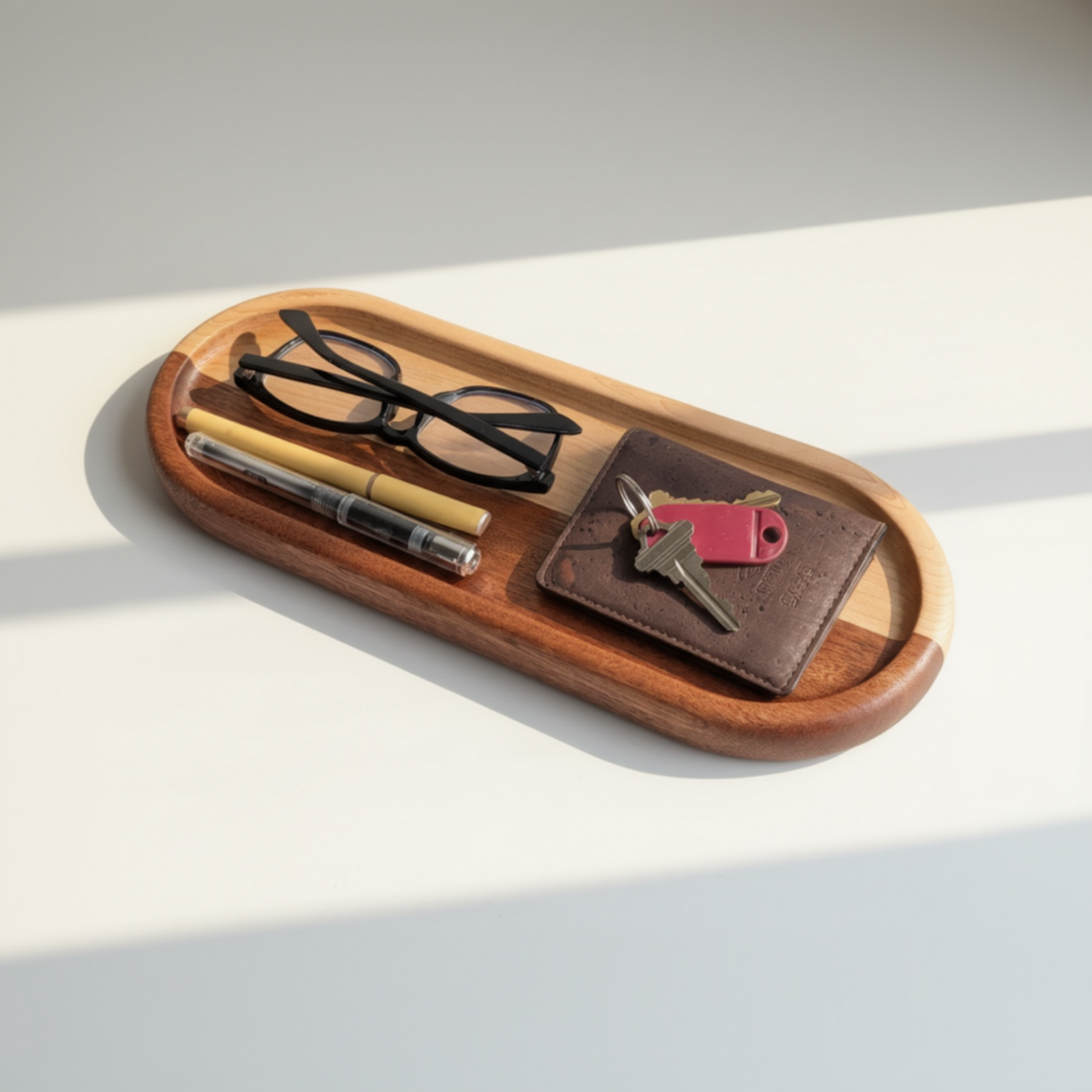 Wooden tray with sunglasses, pen, wallet, and keys on a light background