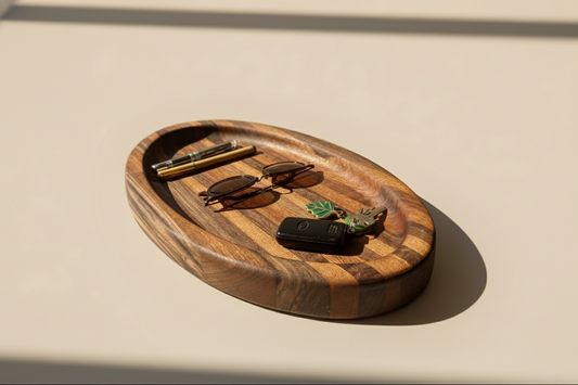 Wooden tray with sunglasses, hairbrush, and key on a beige surface