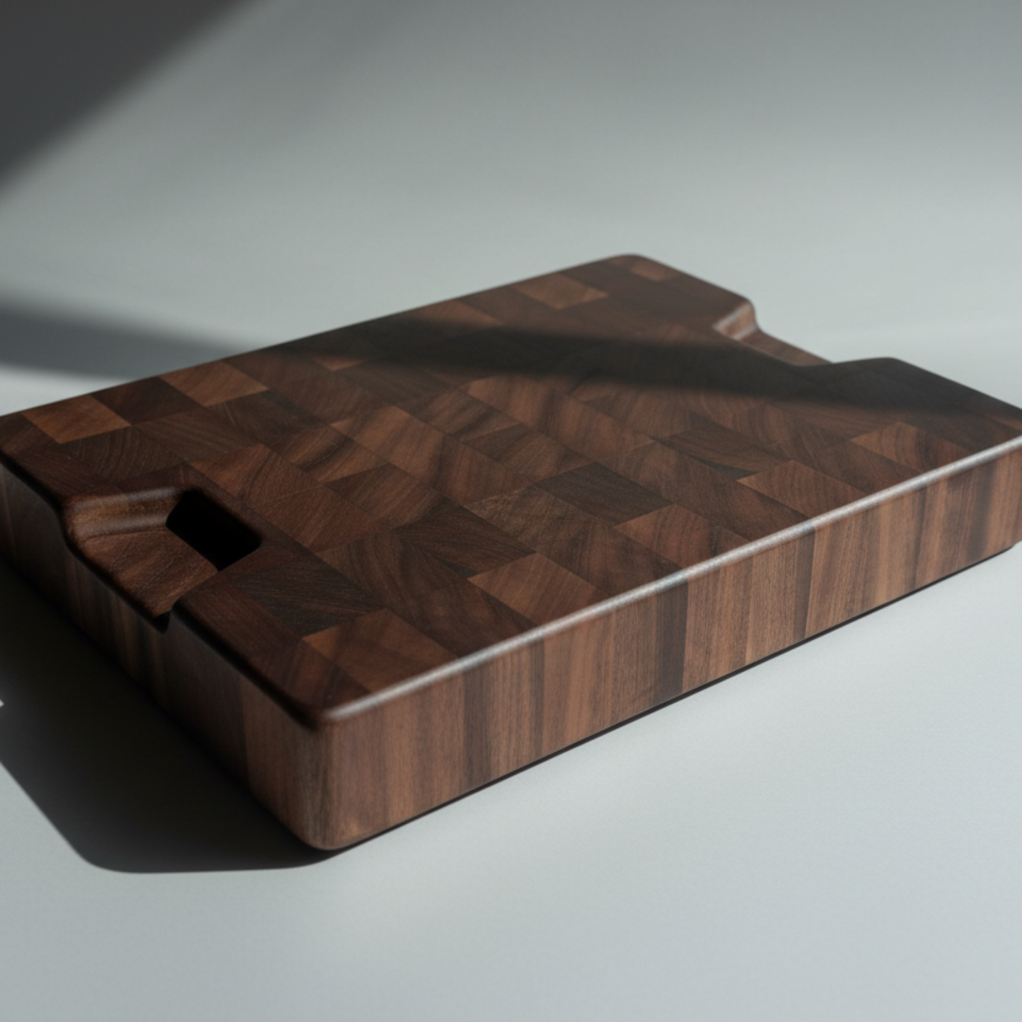 Wooden cutting board with a handle on a light gray background