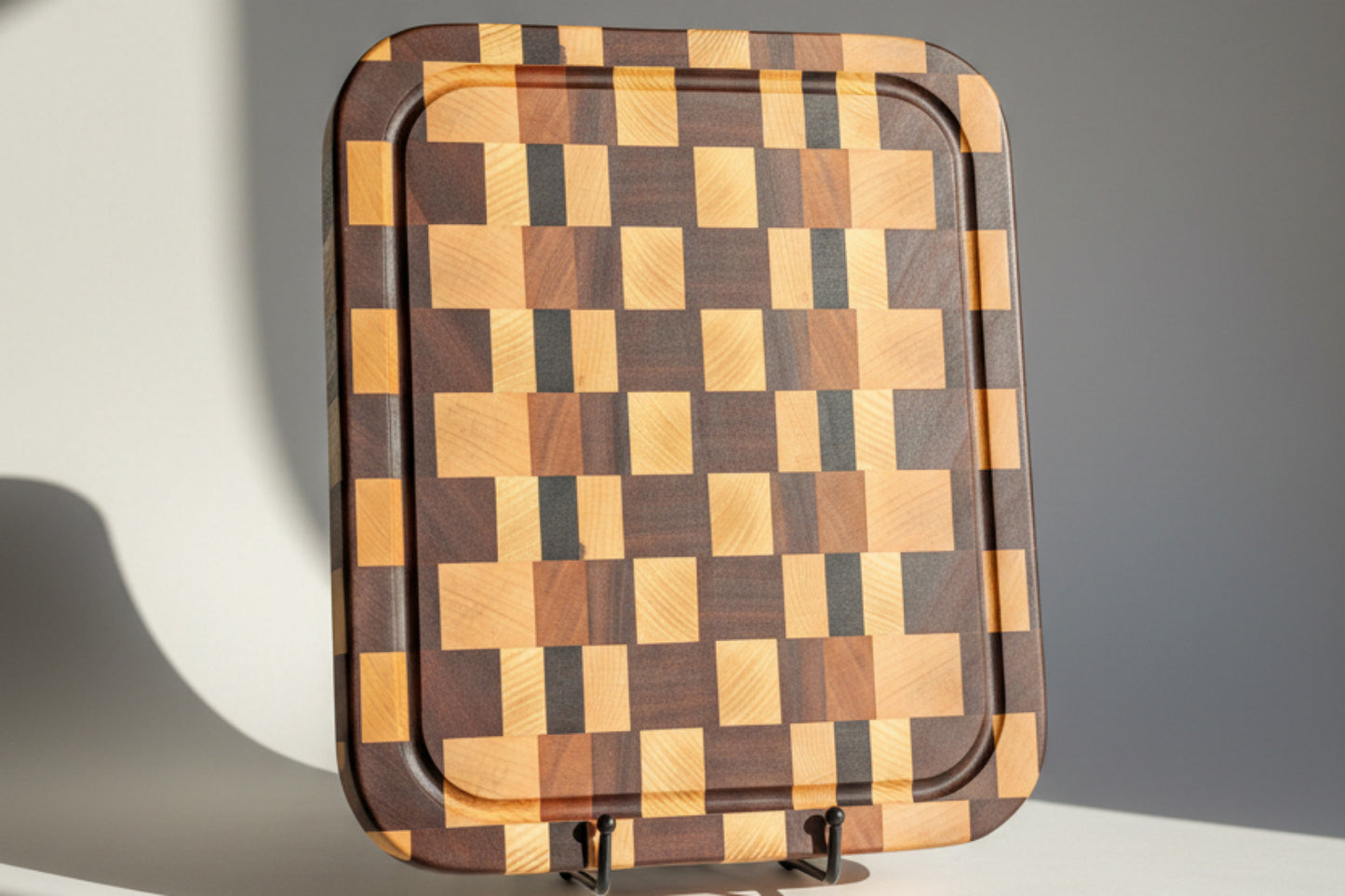 Wooden cutting board with a checkered pattern on a light wooden surface.