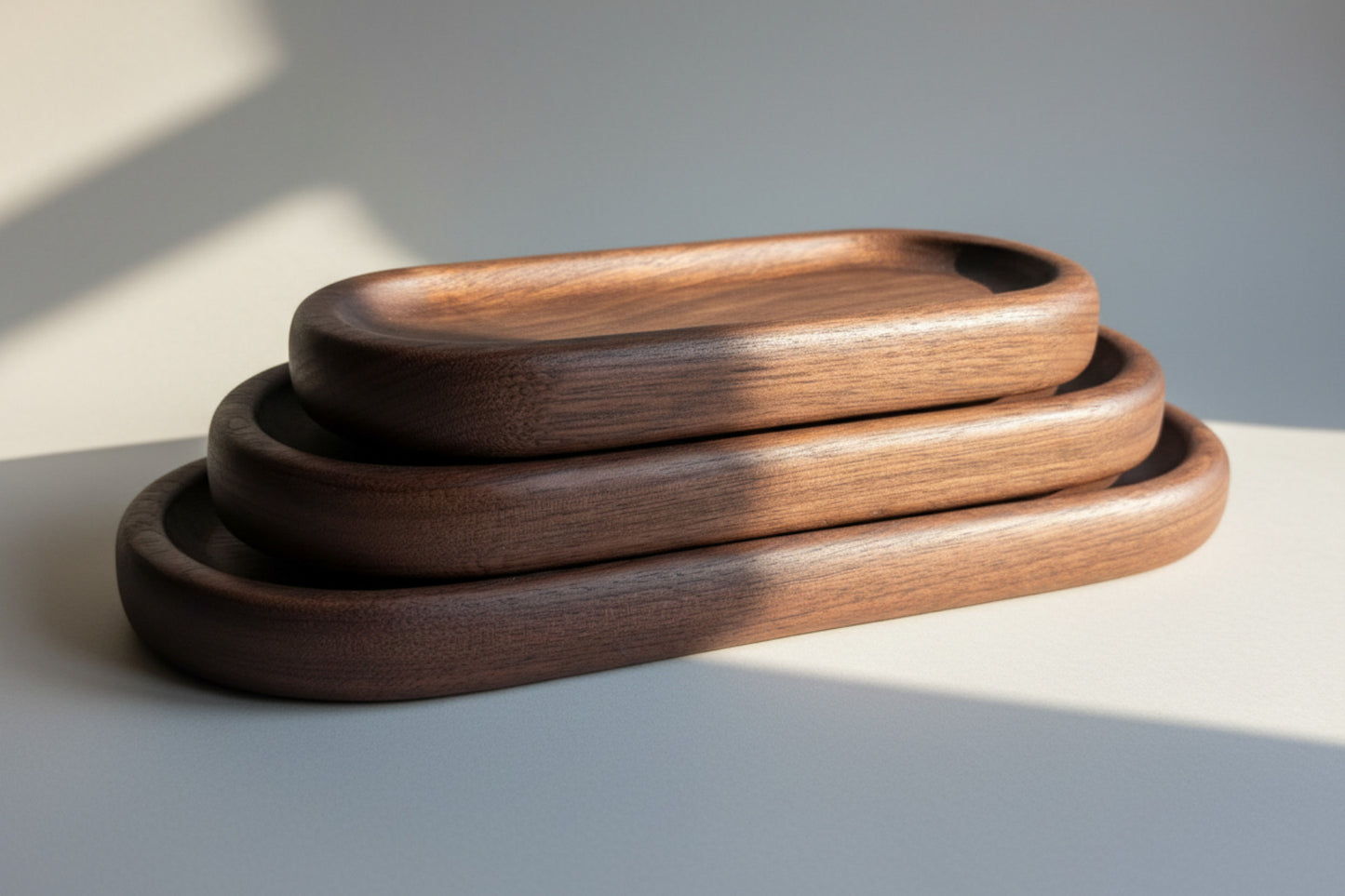 Three wooden trays of different sizes on a light wood surface.