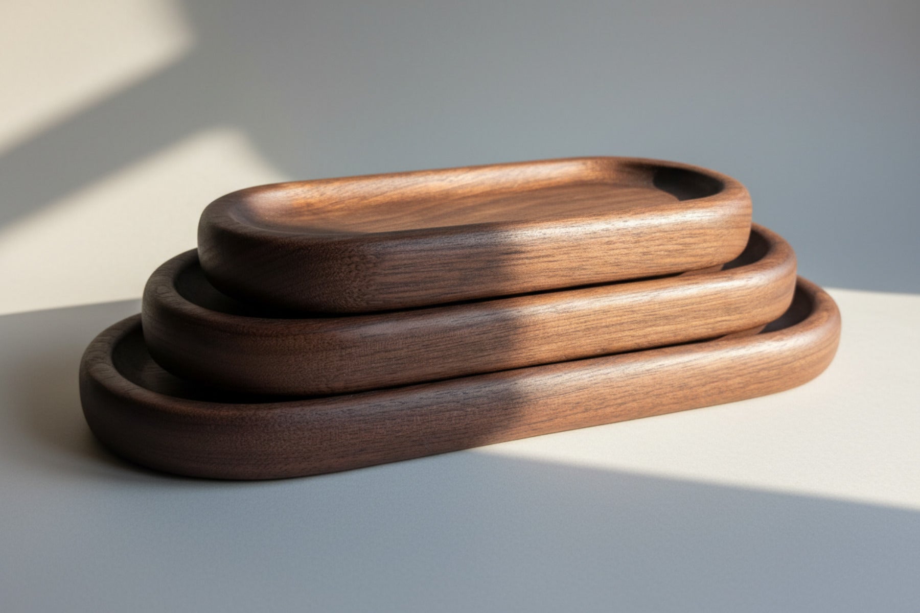 Three wooden trays of different sizes on a light wood surface.