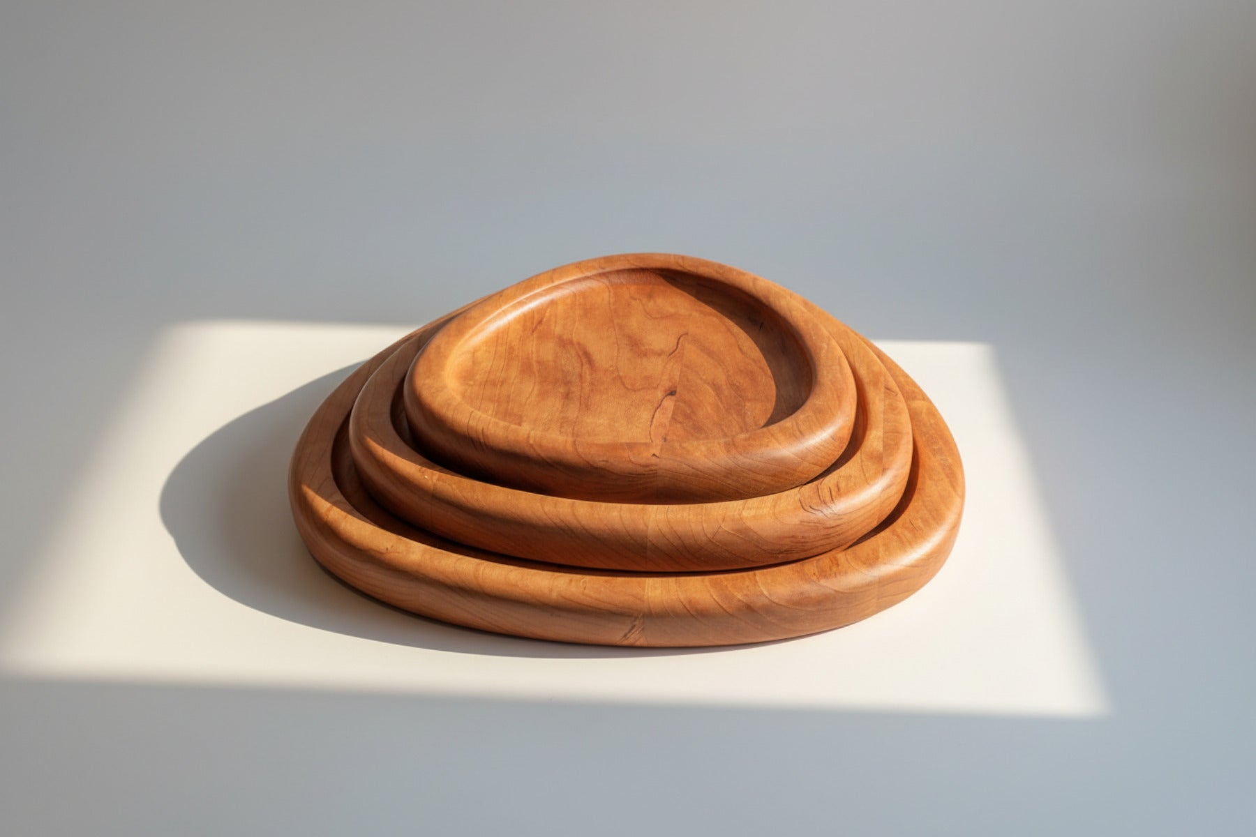 Set of three wooden trays on a patterned fabric background