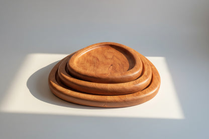 Set of three wooden trays on a patterned fabric background