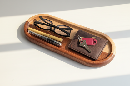 Wooden tray with sunglasses, pen, wallet, and keys on a light background