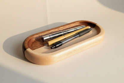 Wooden tray with three pens on a beige background