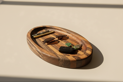 Wooden tray with sunglasses, hairbrush, and key on a beige surface